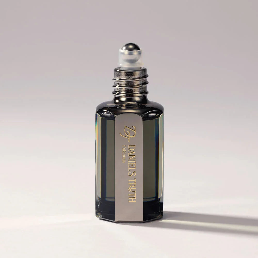 Glass perfume bottle with metal label and rollerball applicator on a neutral background