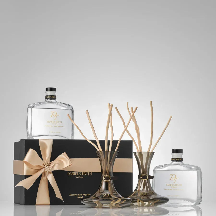 Luxury reed diffuser set with two glass vases, fragrance bottles, gift box, and gold ribbon.