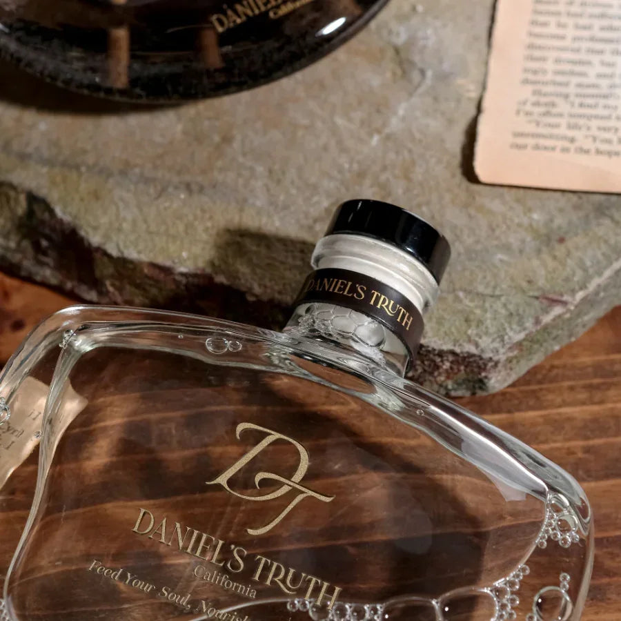 Close-up of a Daniel's Truth glass perfume decanter bottle on a rustic stone surface
