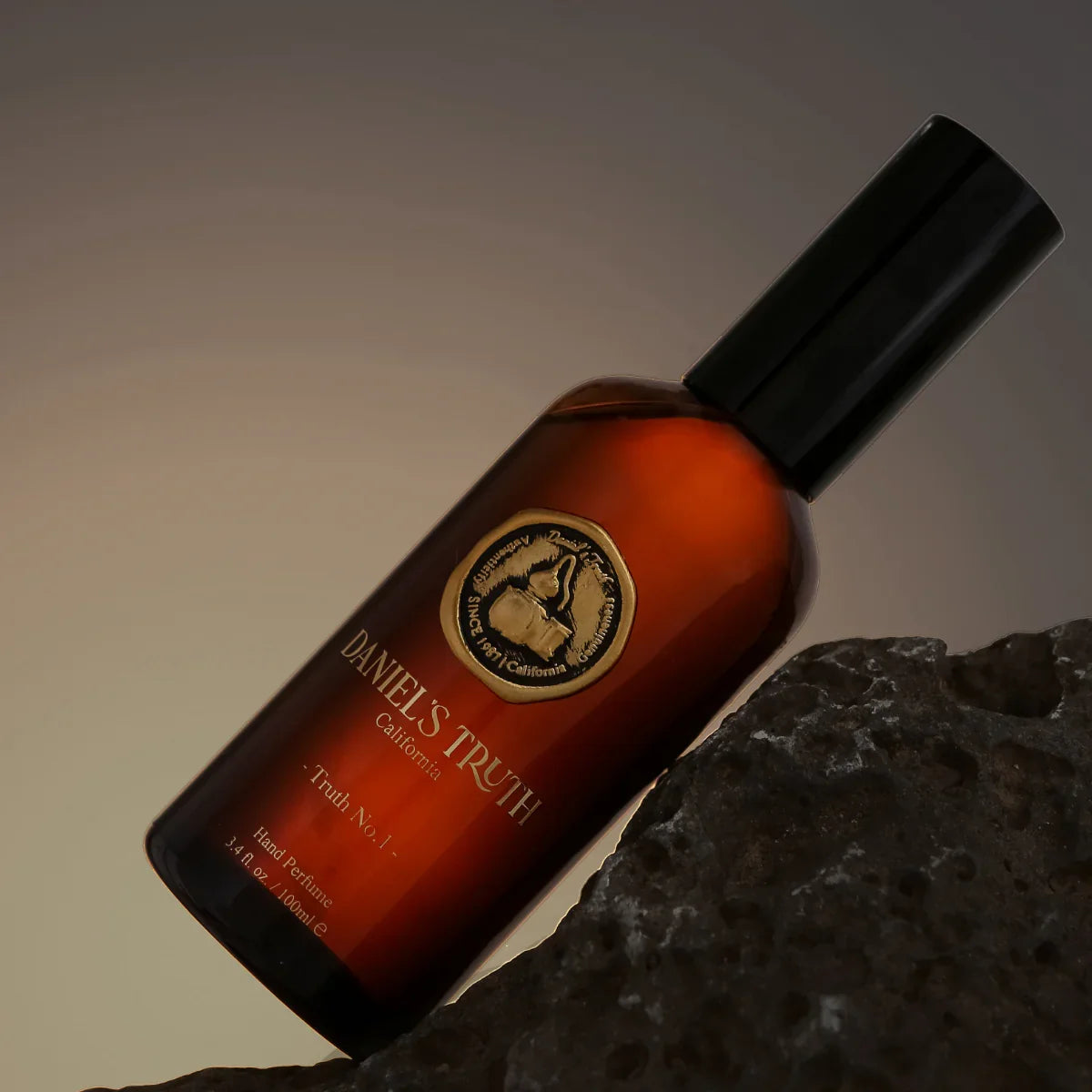 Amber glass perfume bottle labeled Daniel's Truth California on dark textured stone