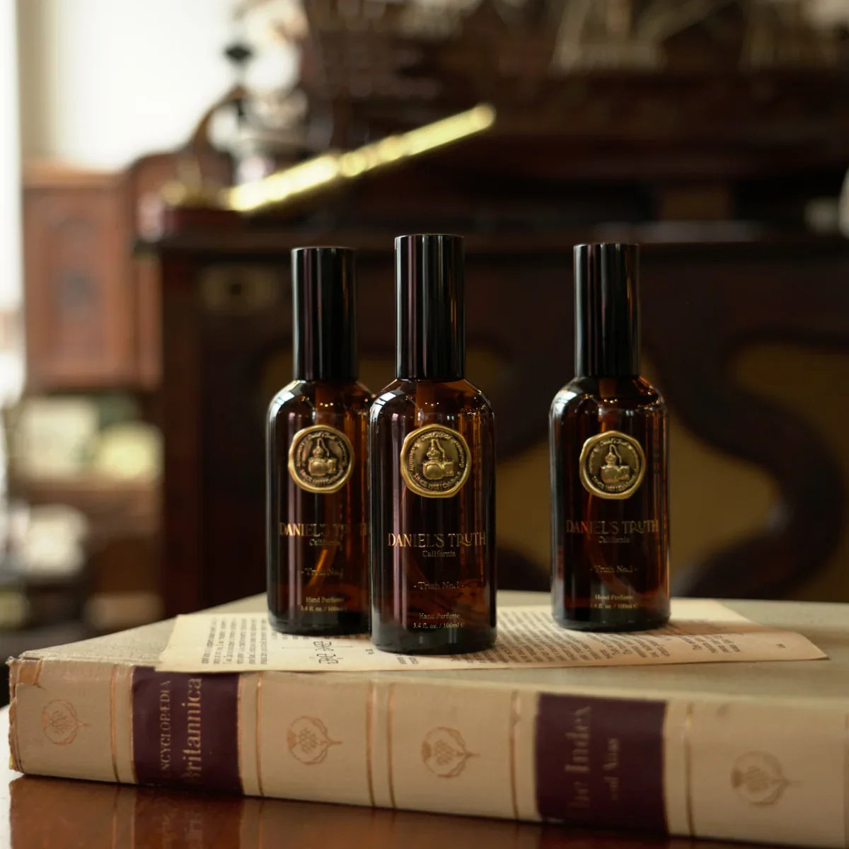 Three brown glass perfume bottles with gold seals on vintage books, elegant setting