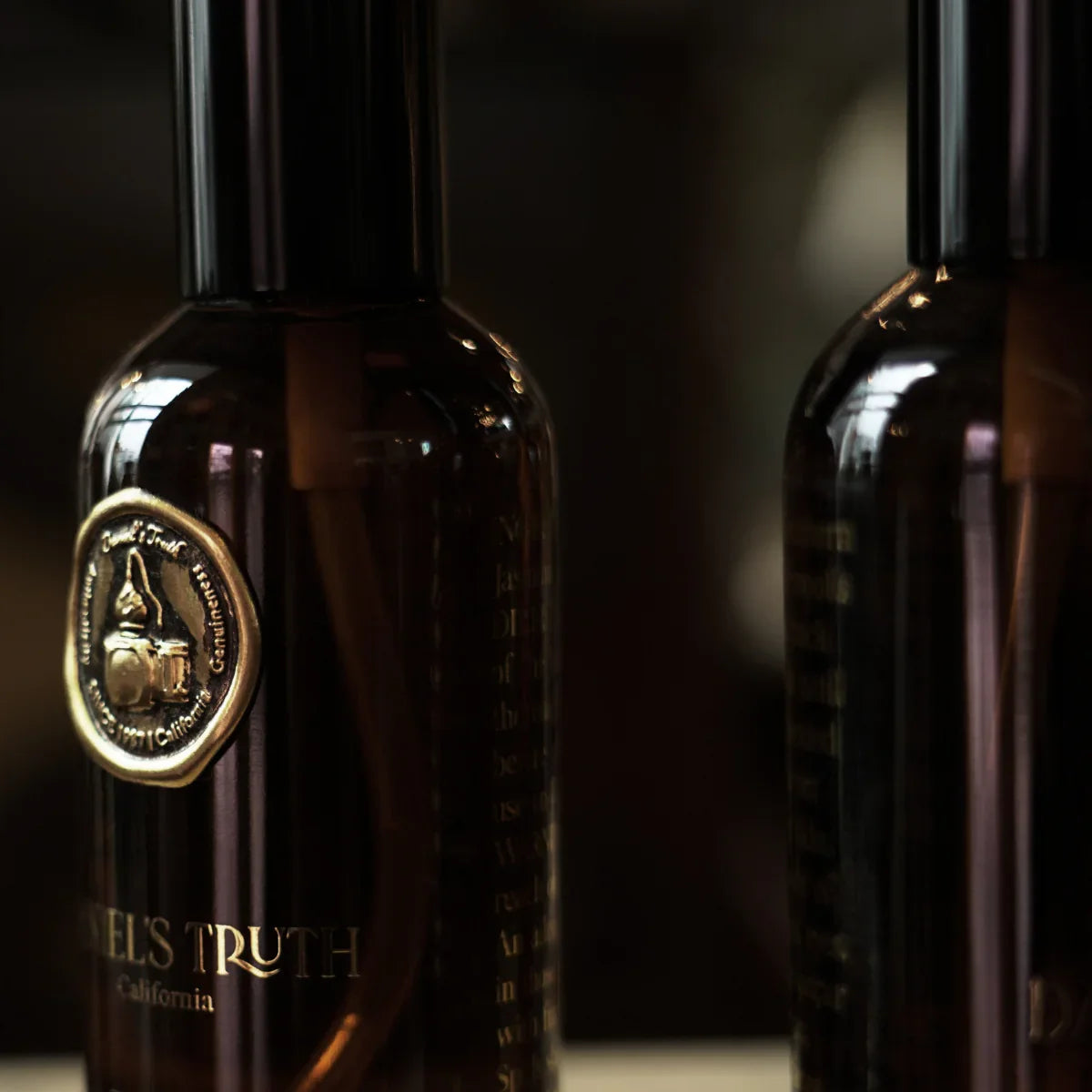Close-up of elegant dark glass perfume bottles with gold embossed label, soft lighting