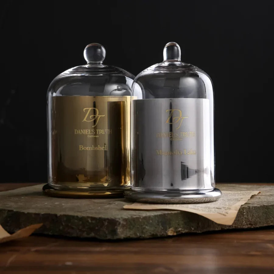 Gold and silver perfume bottles with glass domes on a rustic stone surface